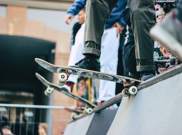 People with skateboards about to drop into a ramp.